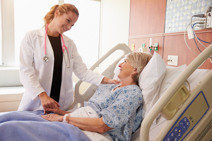 Female Doctor Talks To Senior Female Patient In Hospital Bed Noleggio umidificatori per le camere di un ospedale